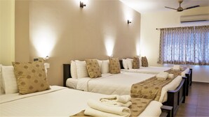 Ein Hotelzimmer mit zwei Betten, beigen Wänden und einem großen Fenster mit Vorhängen.