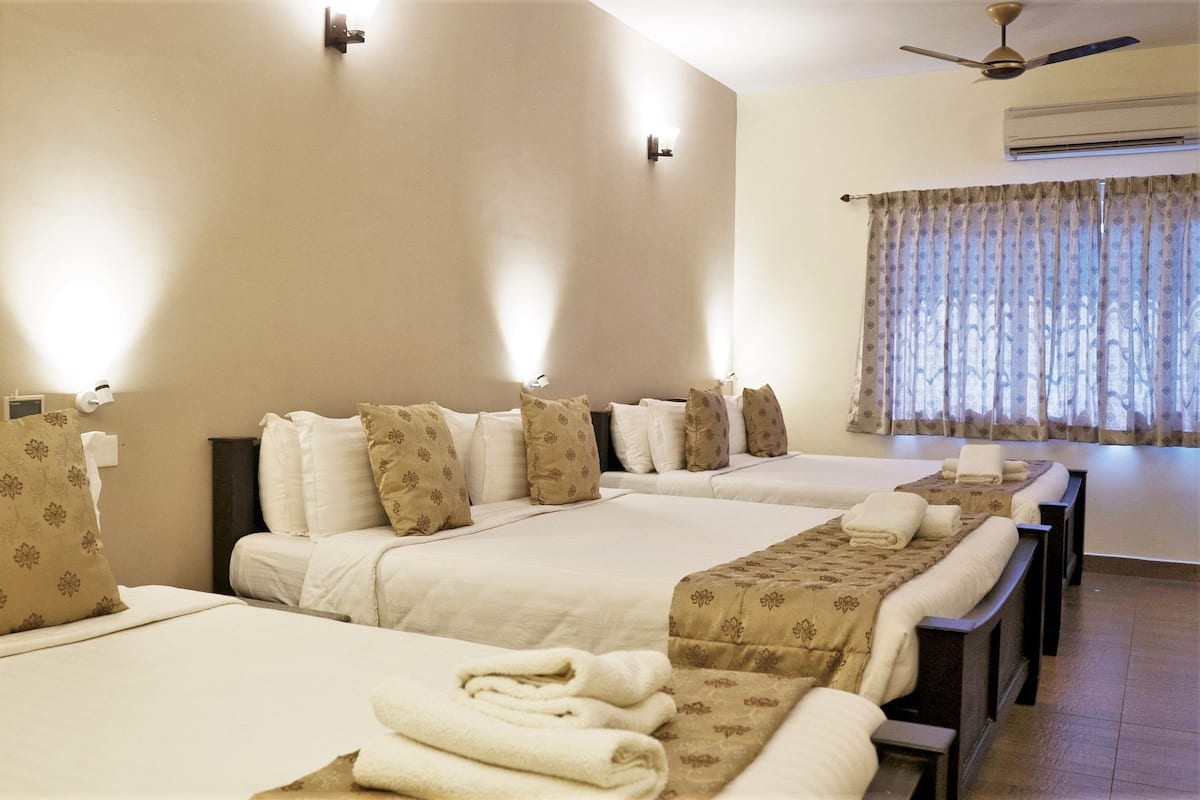 Habitación de hotel con dos camas, paredes color beige y un ventanal con cortinas.