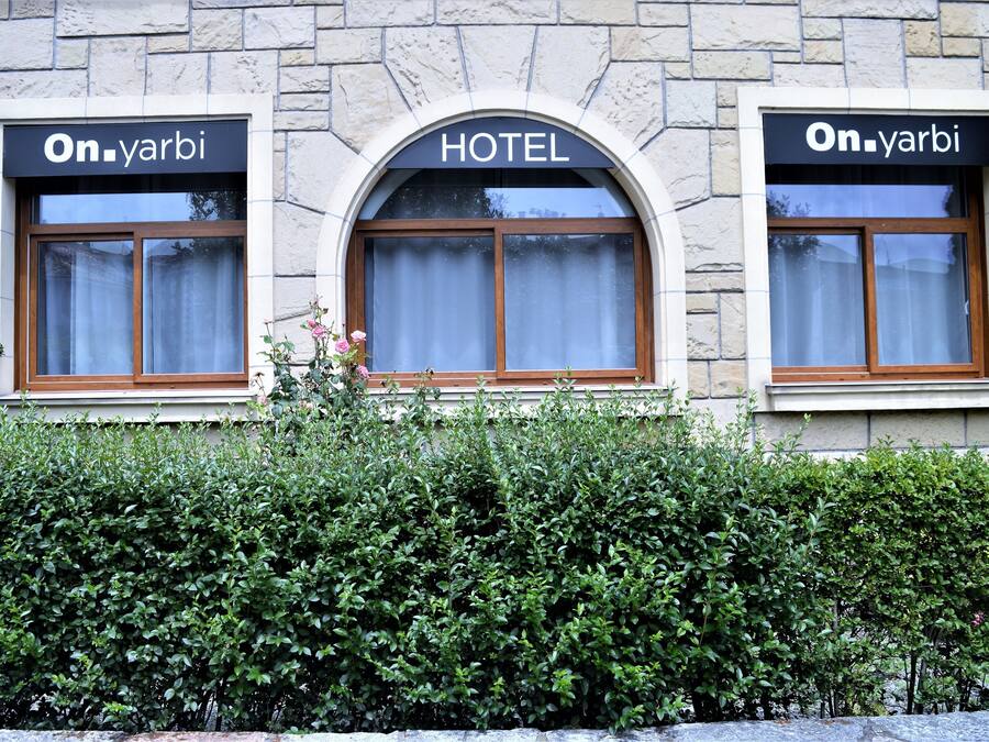 Fachada de hotel con tres ventanas arqueadas, cada una con un cartel que dice 'On.yarbi'.