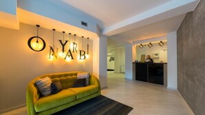 A modern interior with a green sofa, a wall-mounted light fixture spelling out "YARNAB," and a reception area in the background. - Hotel Onyarbi (Hondarribia)