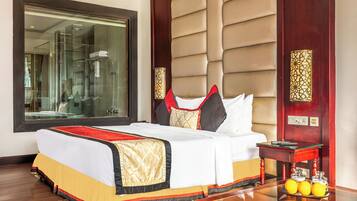 A hotel room with a large bed, a bedside table with a lamp, a mirror, and a view of a bathroom.