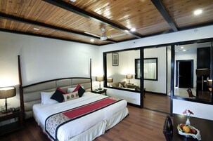 Una habitación de hotel con una cama grande, lámparas de noche, un espejo y techo de madera.