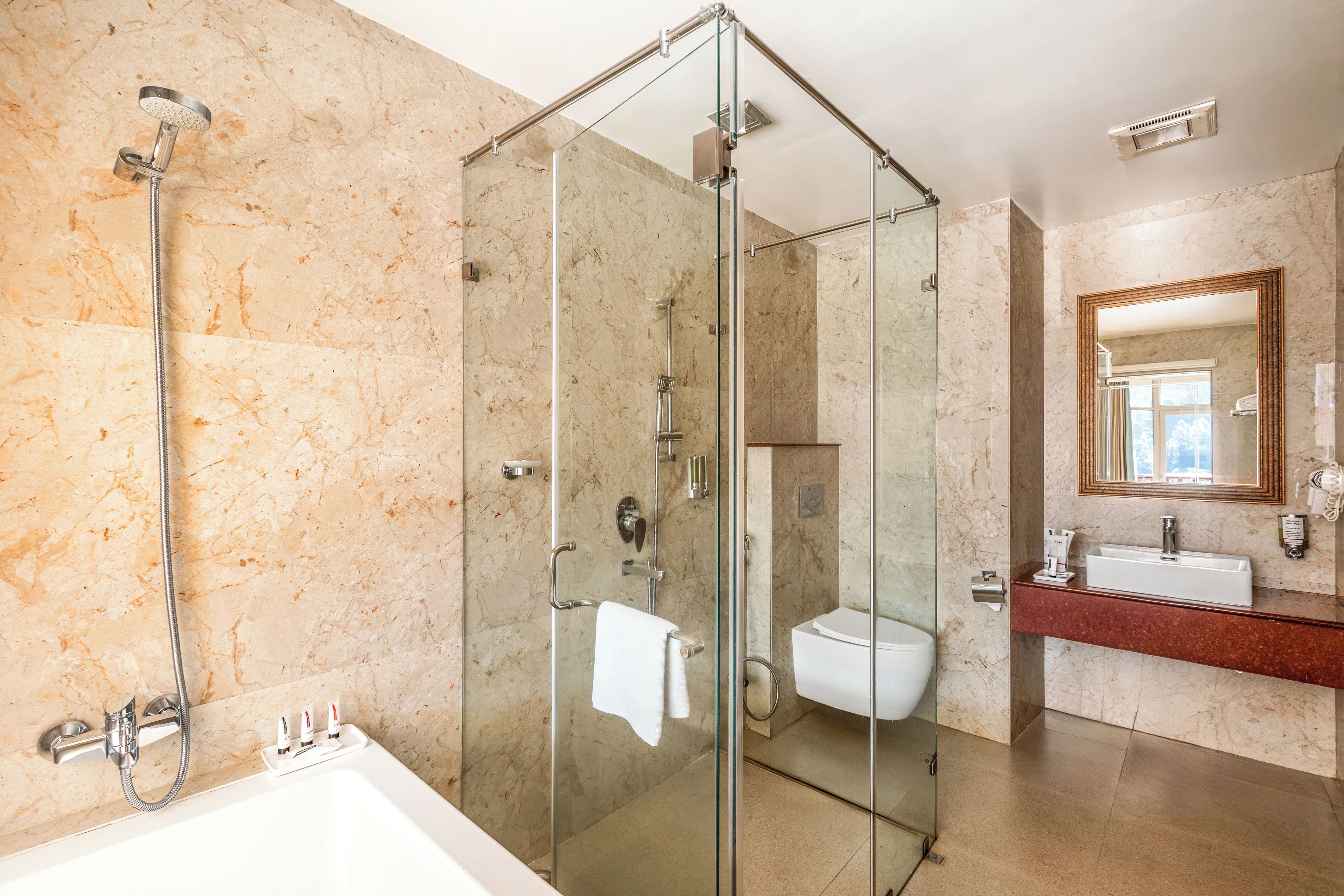 Un baño moderno con ducha de vidrio, bañera blanca y pared con azulejos de mármol.