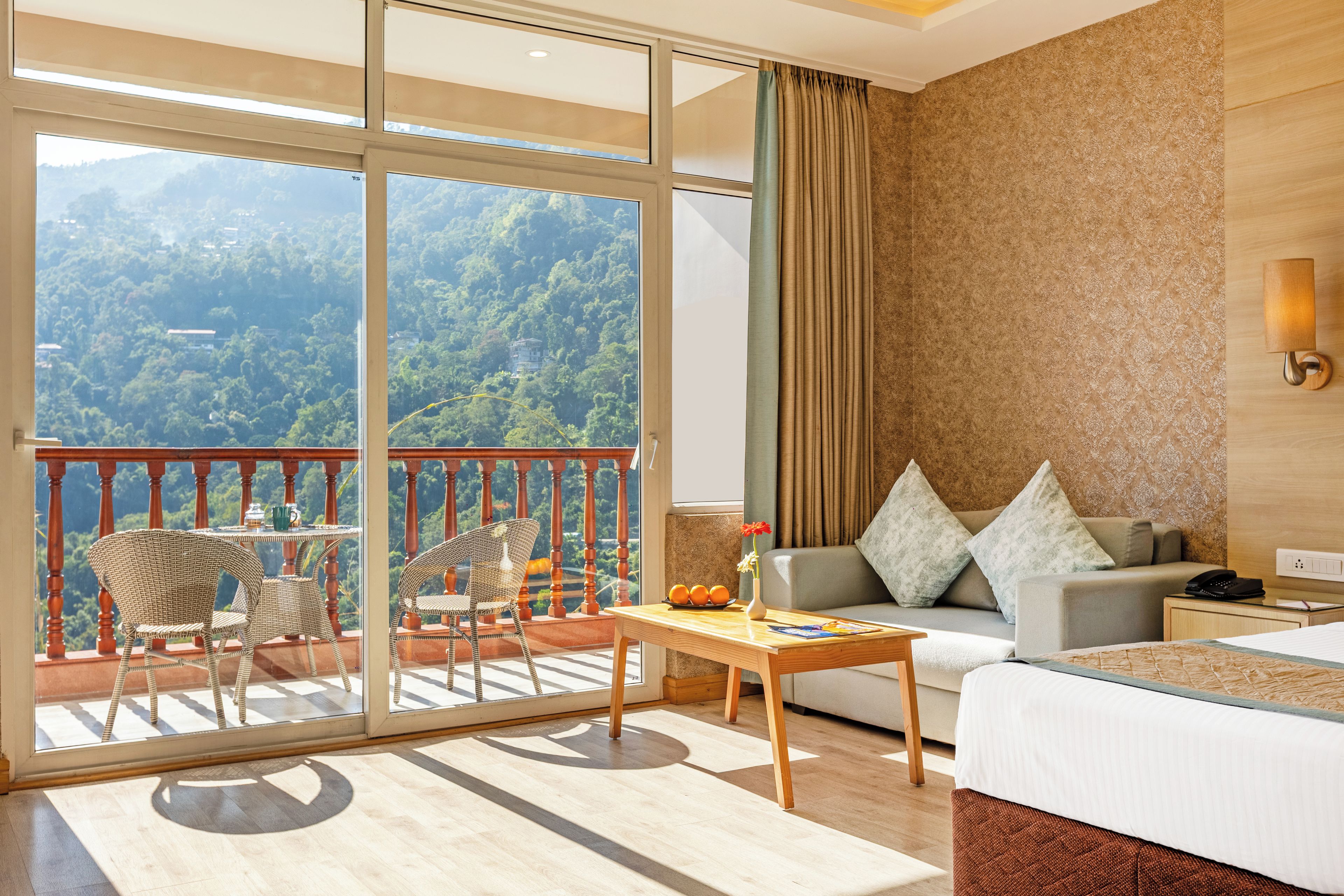 Ein Hotelzimmer mit Balkon, einer Couch, einem Esstisch und einem Bett.