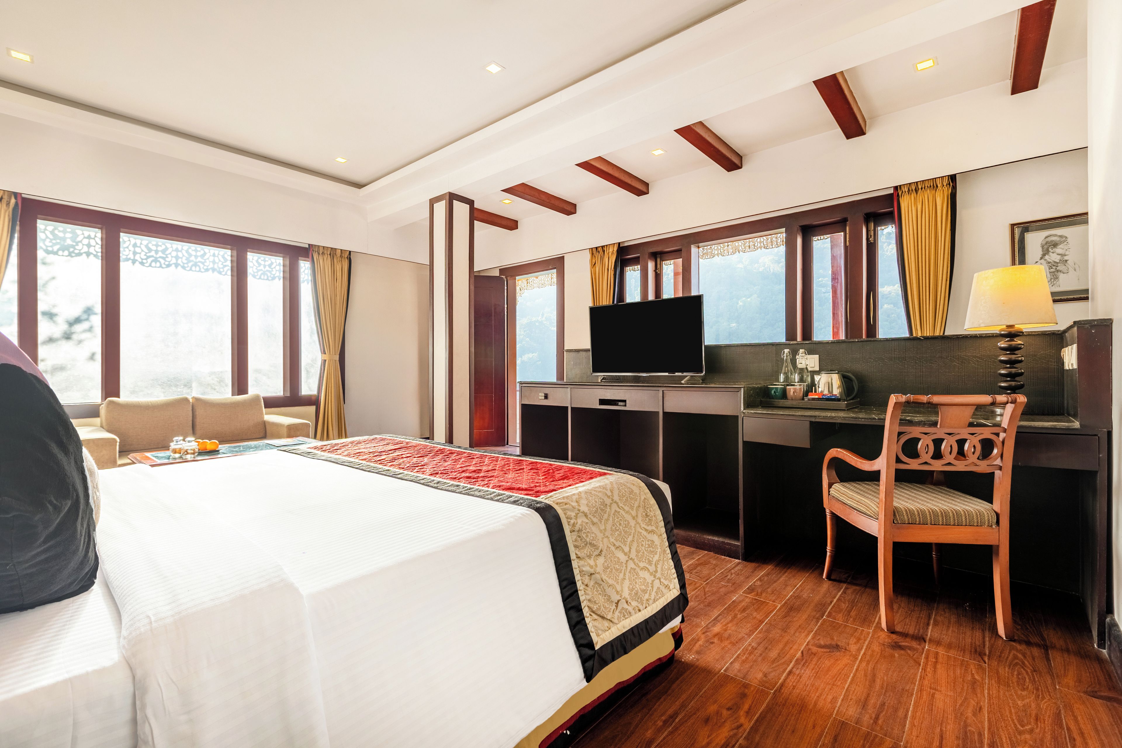 A hotel room with a bed, a desk, a chair, a television, and a window with curtains.