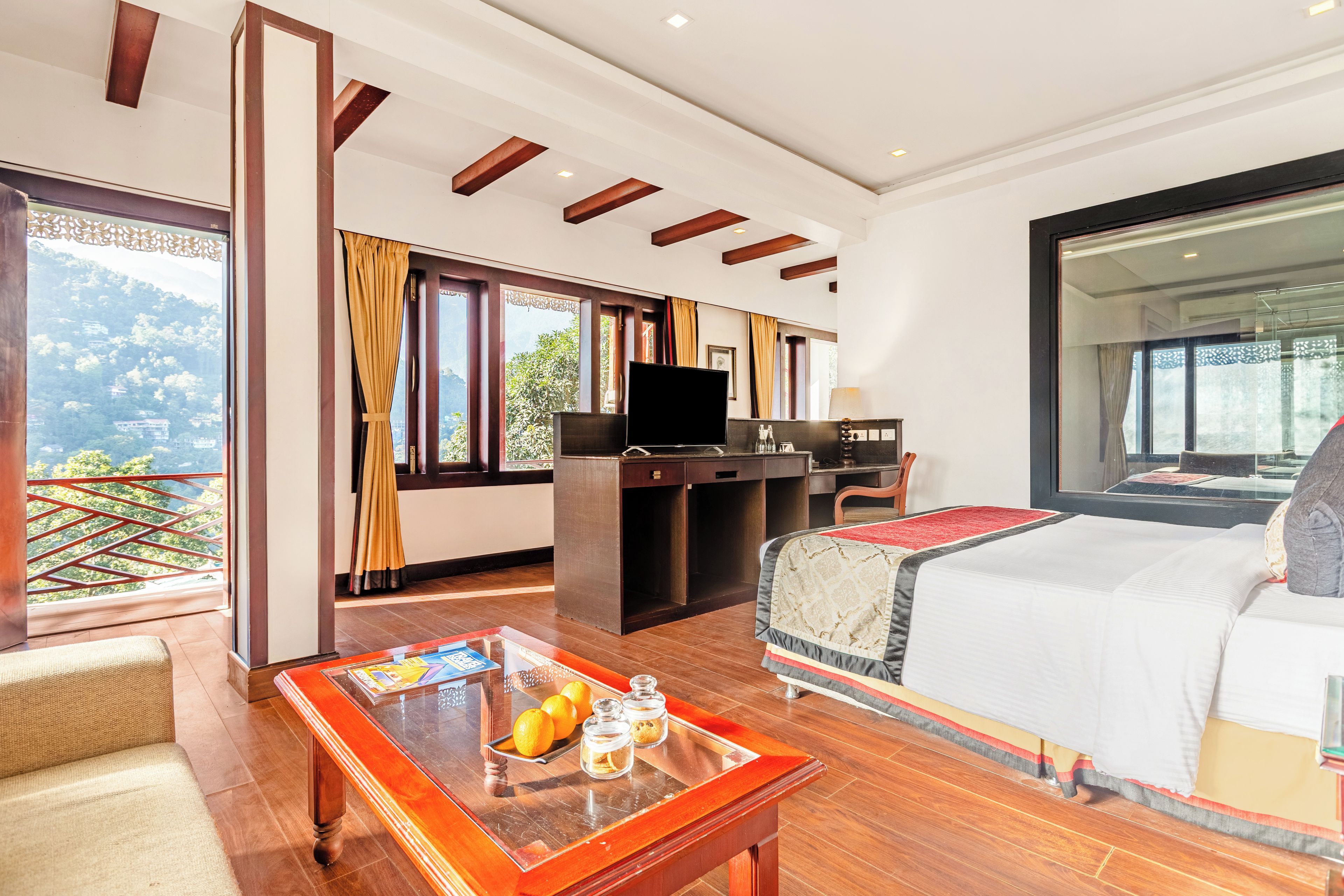 Habitación de hotel con cama, escritorio, televisión y ventana con cortinas.