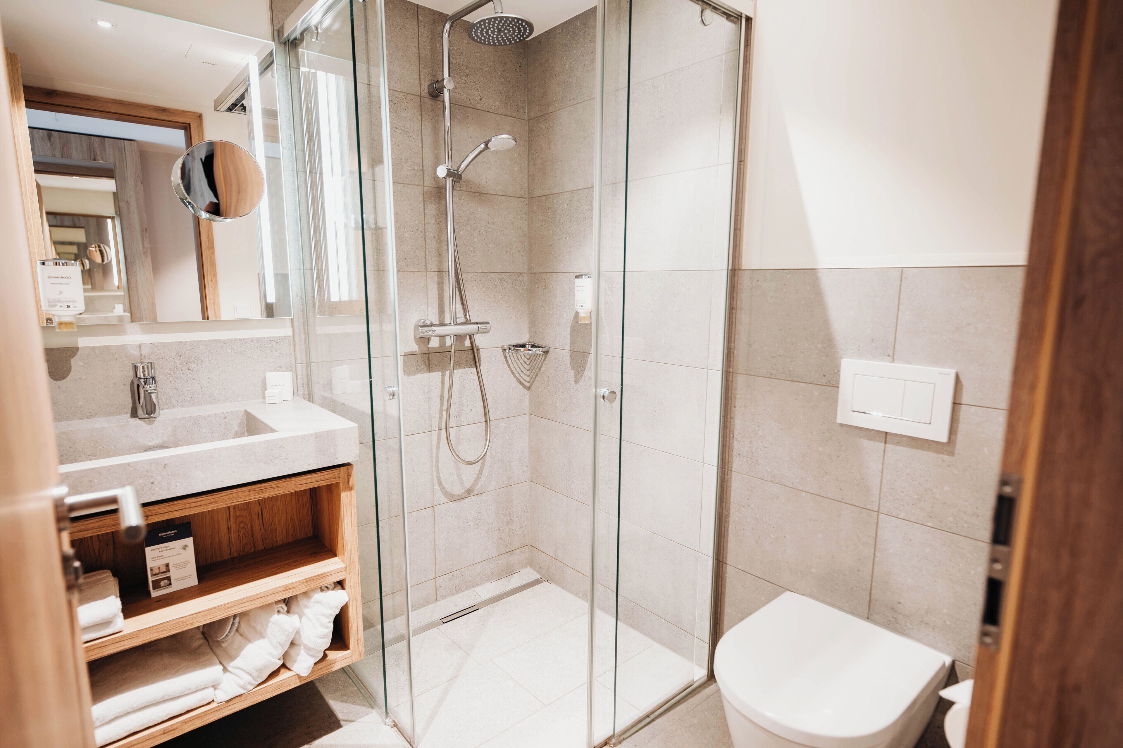 Une salle de bain moderne avec une douche à parois de verre, un lavabo blanc et des toilettes.
