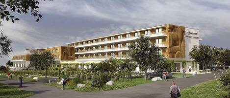 A modern hotel with multiple floors, outdoor seating, and a landscaped garden area.