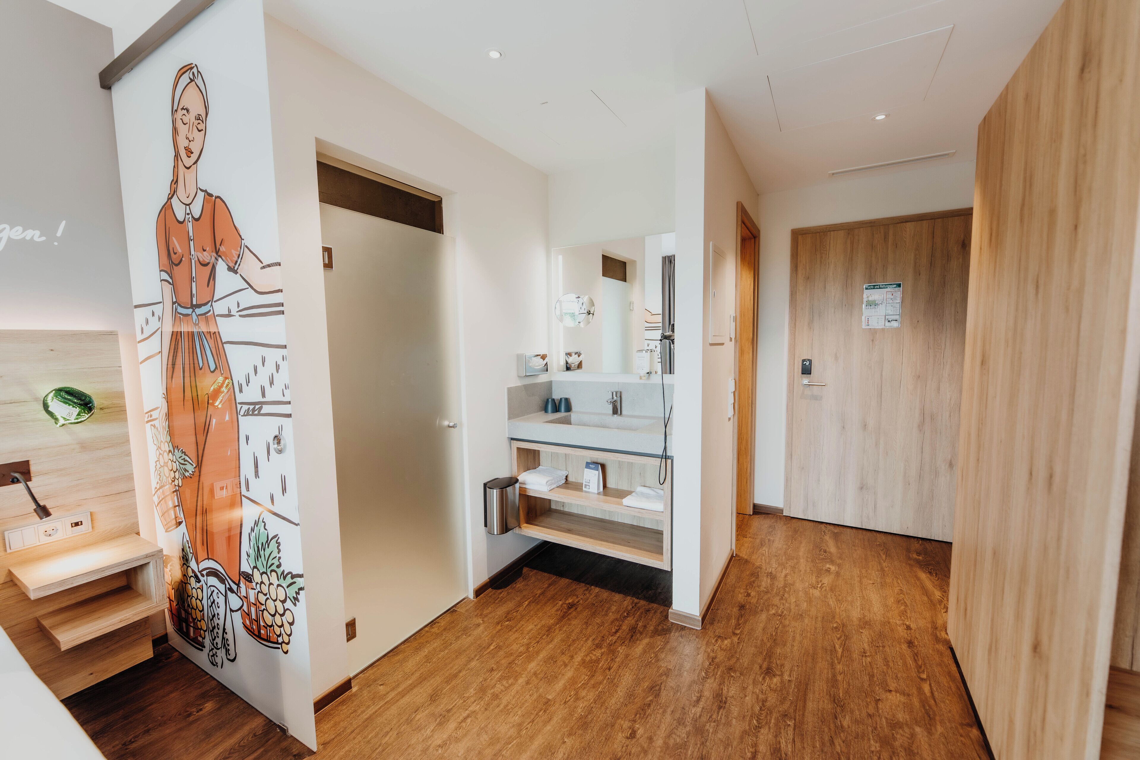 Ein modernes Hotelzimmer mit Holzboden, einer Küchenzeile mit Spüle und einer Wand mit einer Obstillustration.