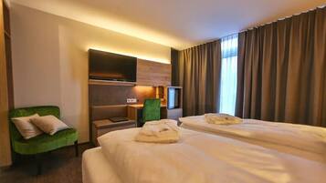 Ein Hotelzimmer mit zwei Betten, einem Schreibtisch, einem Stuhl und einem Fernseher.