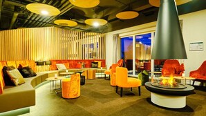 Un salón moderno con sofá, sillones y una chimenea central.