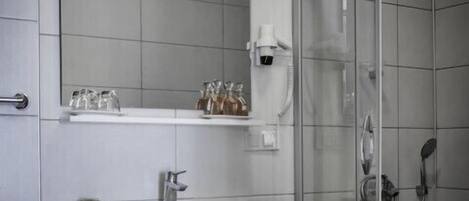 A modern bathroom with a white vanity, a glass shower enclosure, and a mirror above the sink.