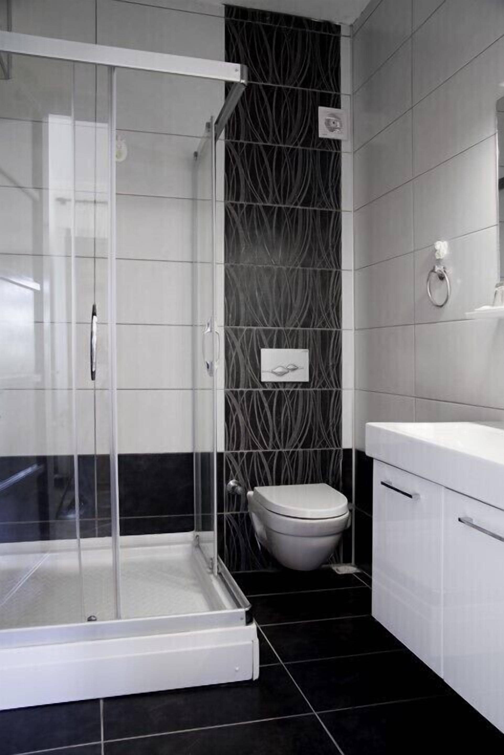 Un baño moderno con ducha de vidrio, inodoro blanco y lavamanos blanco con espejo.