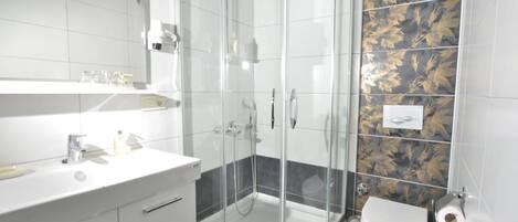 Un baño moderno con ducha de vidrio, lavamanos blanco y un inodoro.
