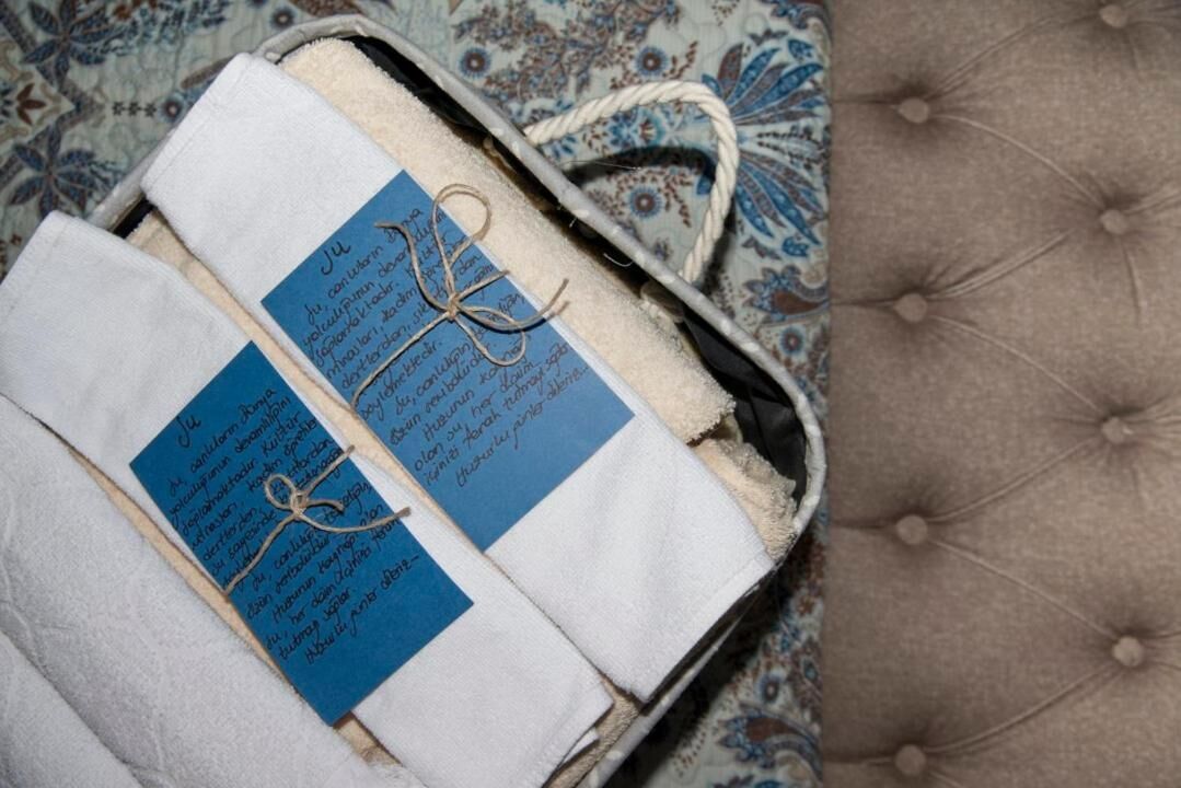 Maleta amb dues etiquetes blaves subjectes a draps blancs, damunt d'una superfície de teixit estampat.