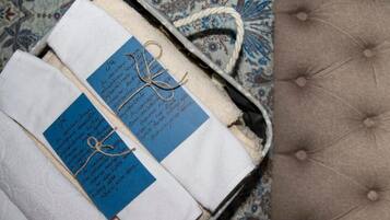Maleta amb dues etiquetes blaves subjectes a draps blancs, damunt d'una superfície de teixit estampat.