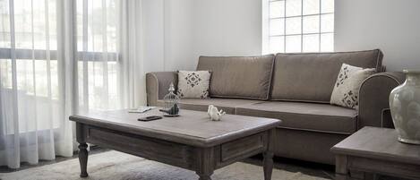 A living room with a sofa, two side tables, a coffee table, and a rug.