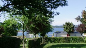 A row of mobile homes with a lake view. - Camping Parc de Charouzech (Salles-Curan)