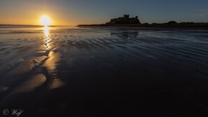 Ein Strand mit einer Burg im Hintergrund bei Sonnenuntergang.