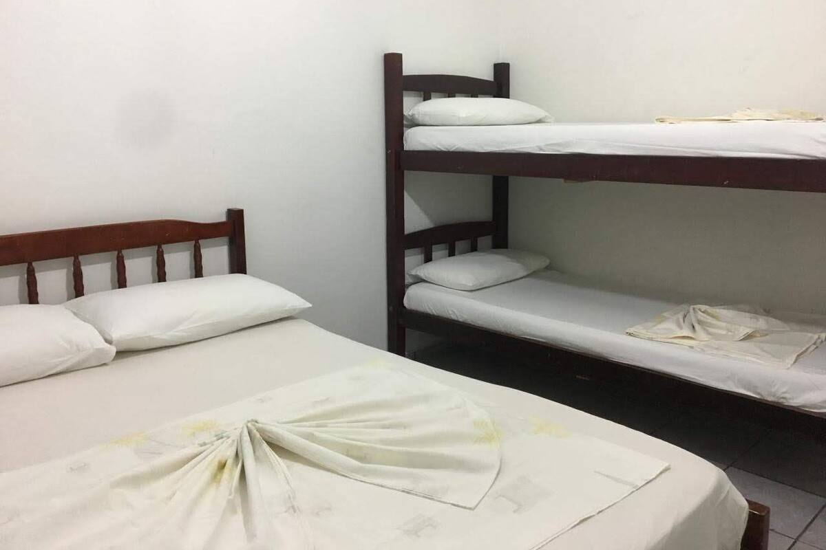 A bunk bed room with two beds, each with white bedding and pillows.