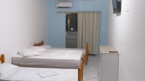 A small, clean room with a bed, a desk, and a TV on the wall. - Pousada Verdes Mares (Guaratuba)
