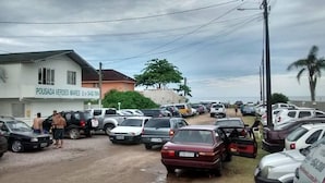 A parking lot with multiple cars and a building labeled "POUSADA VERDES MARES" with a contact number. - Pousada Verdes Mares (Guaratuba)