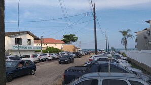 A parking lot with multiple cars, a building with a sign reading "POUSADA VERDES MARES", and a view of the sea in the background. - Pousada Verdes Mares (Guaratuba)