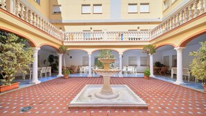 A courtyard with a central fountain, white columns, and a tiled floor. - Micampus Málaga (Málaga)