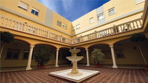 A courtyard with a central fountain, potted plants, and a tiled floor. - Micampus Málaga (Málaga)