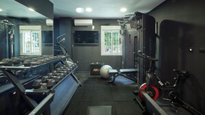 A gym with weight racks, an exercise bike, and a large mirror. - Micampus Málaga (Málaga)