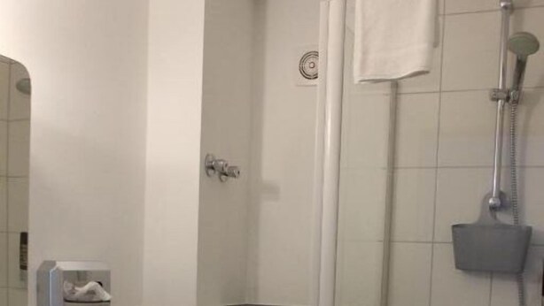 Un baño pequeño y funcional con inodoro, lavamanos y ducha.