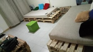 A room with a bed on a wooden pallet, a green storage box, and a painting on the wall. - Jamhuri Home 2 (Nairobi)