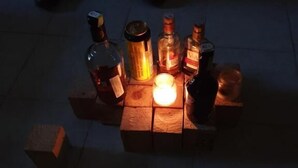 A table with various bottles and a lit candle, set on a tiled floor. - Jamhuri Home 2 (Nairobi)