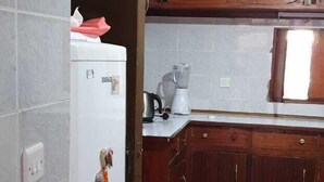 A kitchen with wooden cabinets, a white refrigerator, and a countertop with a blender. - Jamhuri Home 2 (Nairobi)