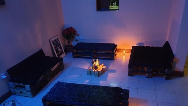 A room with a sofa set, a small table with candles, and a wall-mounted TV. - Jamhuri Home 2 (Nairobi)