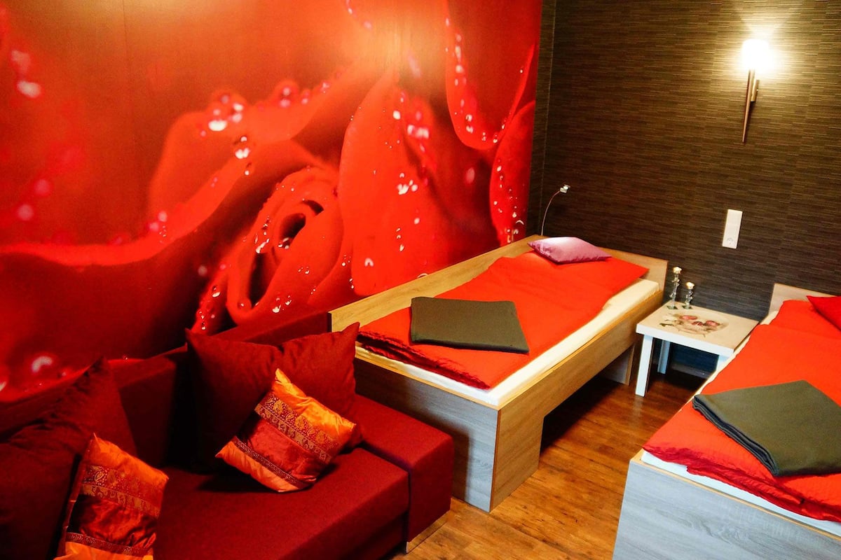A room with a wooden bed, a red sofa, and a small table with candles.