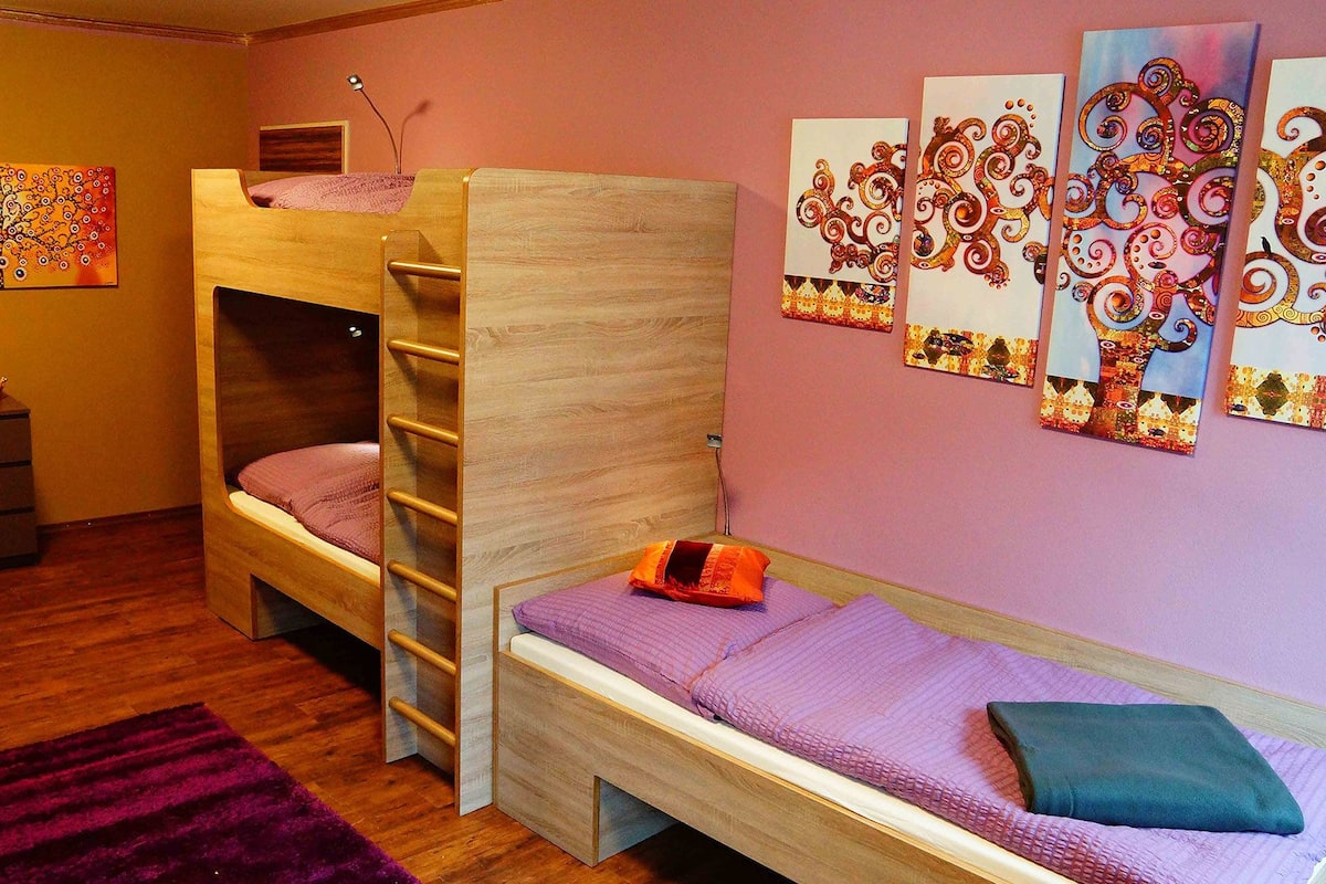 A room with bunk beds, a dresser, and wall art.