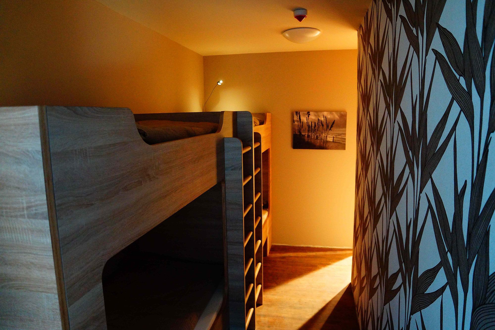 Habitación con literas, cabecera de madera, estante en la pared y un cuadro enmarcado.