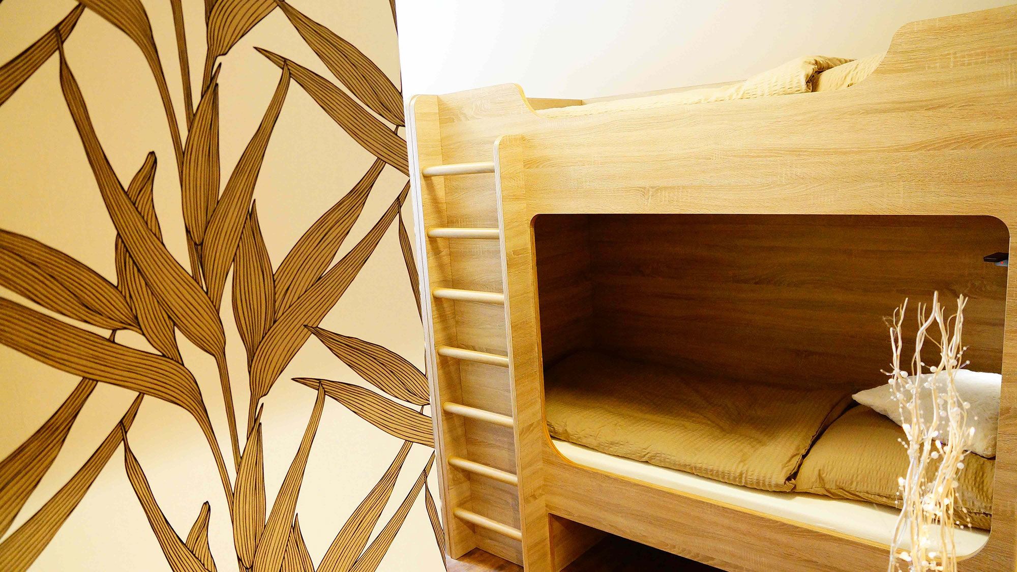 Una litera con una escalera, un cojín y una pequeña planta decorativa.