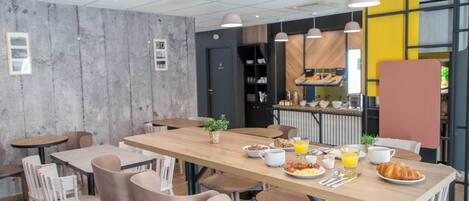 Ein stilvoller Essbereich mit einem langen Holztisch, mehreren Stühlen und einem Frühstücksbuffet mit Müsli, Eiern und Orangensaft.