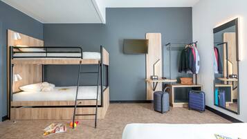 A modern hotel room with bunk beds, a desk, a mirror, and a wardrobe.