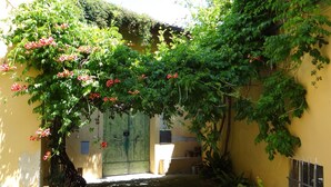 A narrow alleyway with a yellow wall, a green door, and potted plants. - Pian dei Giullari Suite (Florence)