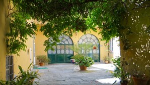 A courtyard with a yellow building, green door, and potted plants. - Pian dei Giullari Suite (Florence)