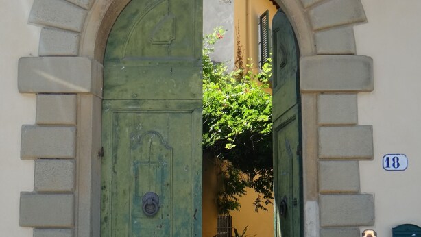 An arched doorway with a green door, a mailbox, and a house number 18. - Pian dei Giullari Suite (Florence)