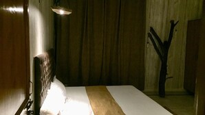 A room with a bed, a hanging light fixture, and a wooden structure resembling a tree. - Rooming House (Greater Noida)