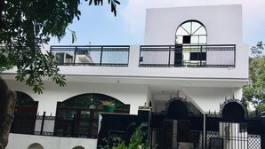 A two-story building with a white facade, black railings, and a large arched window on the upper floor. - Rooming House (Greater Noida)