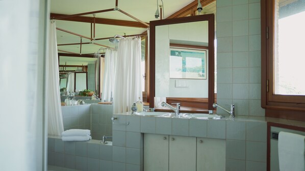 A bathroom with a large mirror, two sinks, a shower, and a window. - Antico Castello Marignolle (Florence)