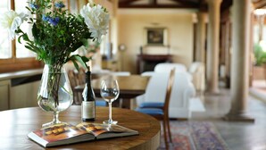 A dining area with a wooden table, a vase with flowers, a wine bottle, and a wine glass. - Antico Castello Marignolle (Florence)