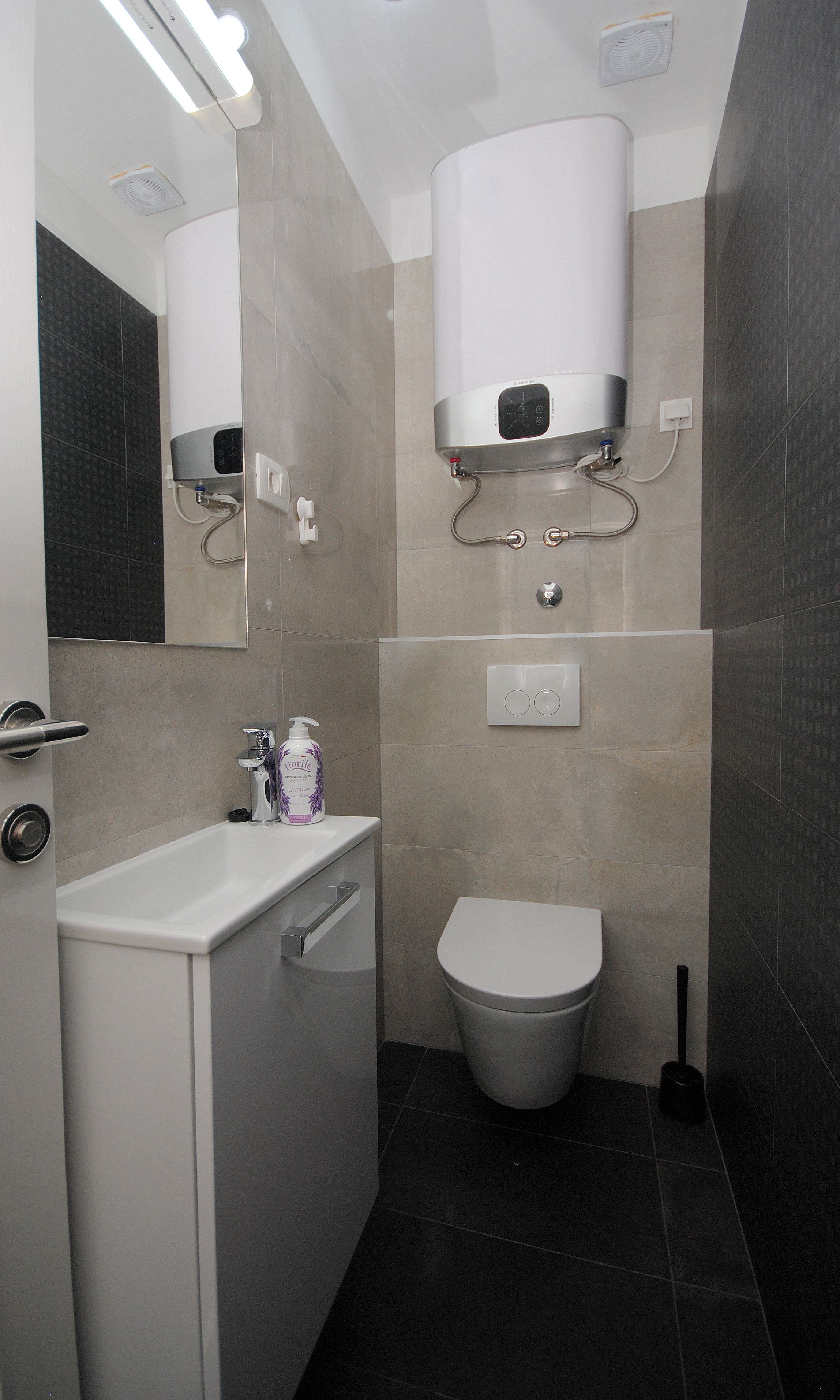 A modern bathroom with a toilet, sink, and mirror.