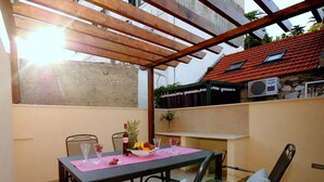 A covered patio with a table set for two, surrounded by metal chairs.